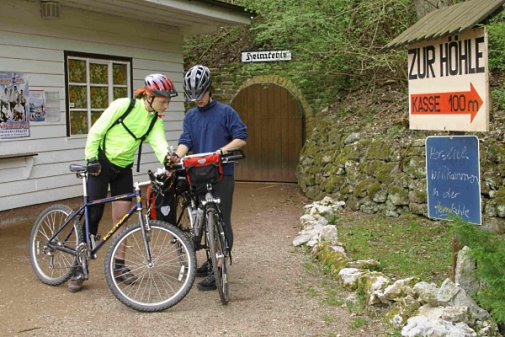 [billede: to cyklister, hulens indgang i baggrund]